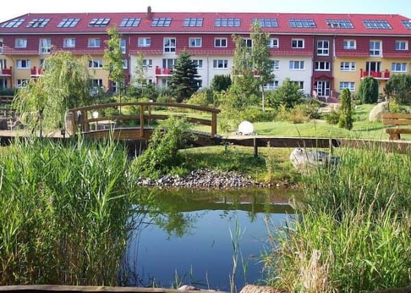 Gartenanlage mit Teich und Holzbrücke vor den Häusern