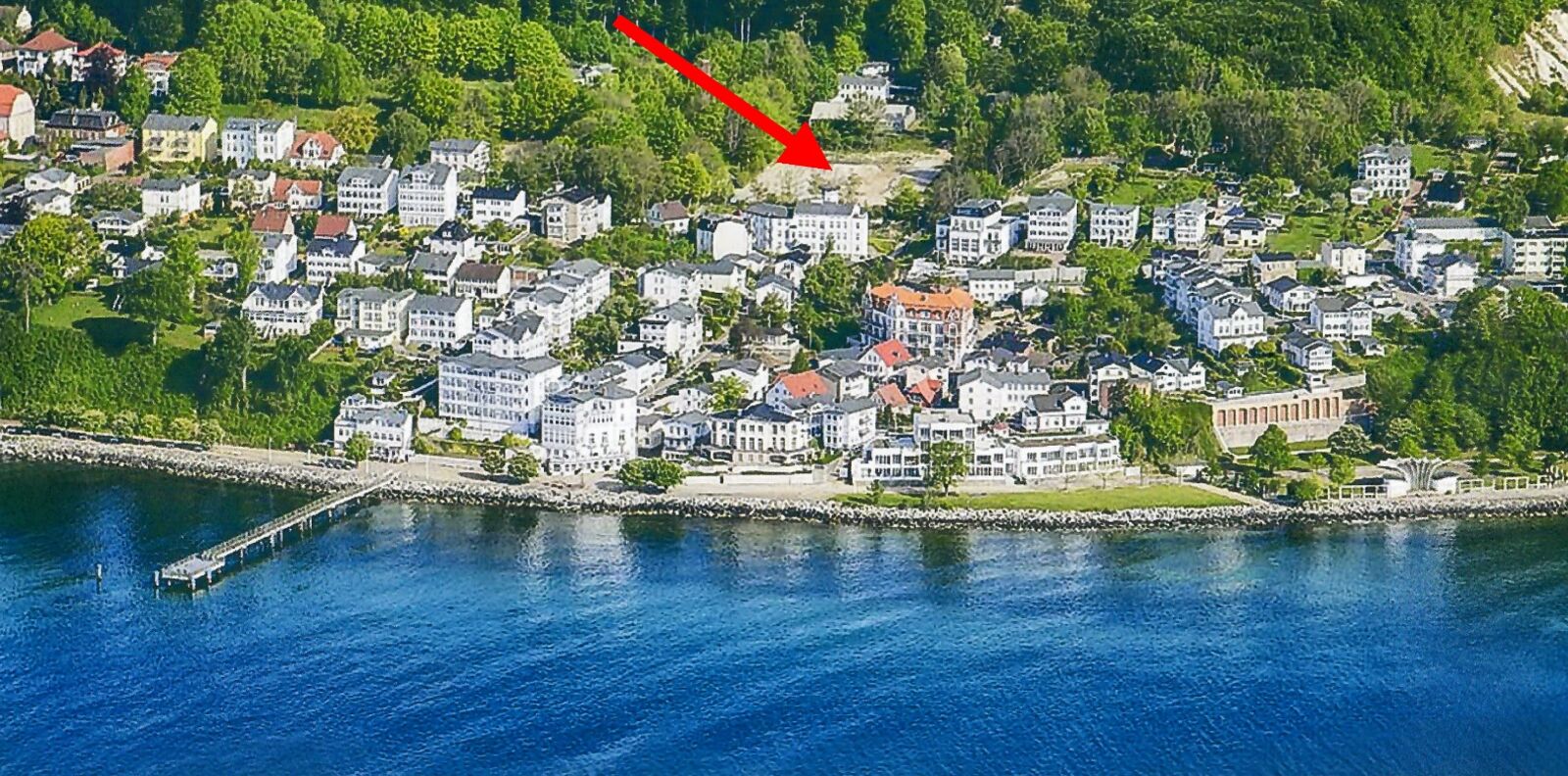 Luftbild von Sassnitz mit Seebrücke und Ortskern, ein roter Pfeil markiert die Lage des Grundstücks am Hang