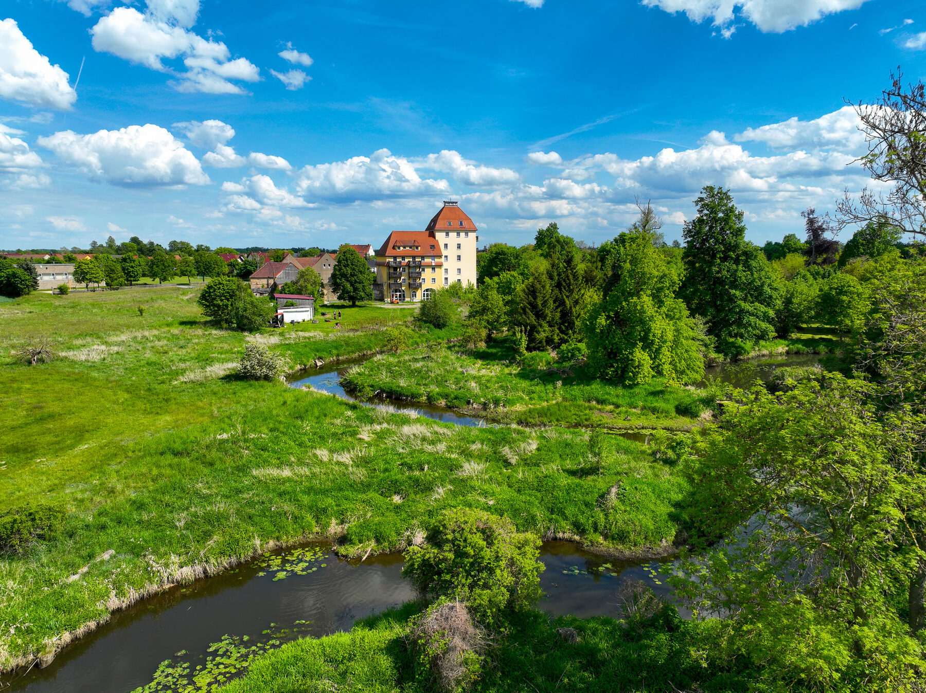 Flussaue der Röder mit Wiesen, im Hintergrund die Schlossmühle