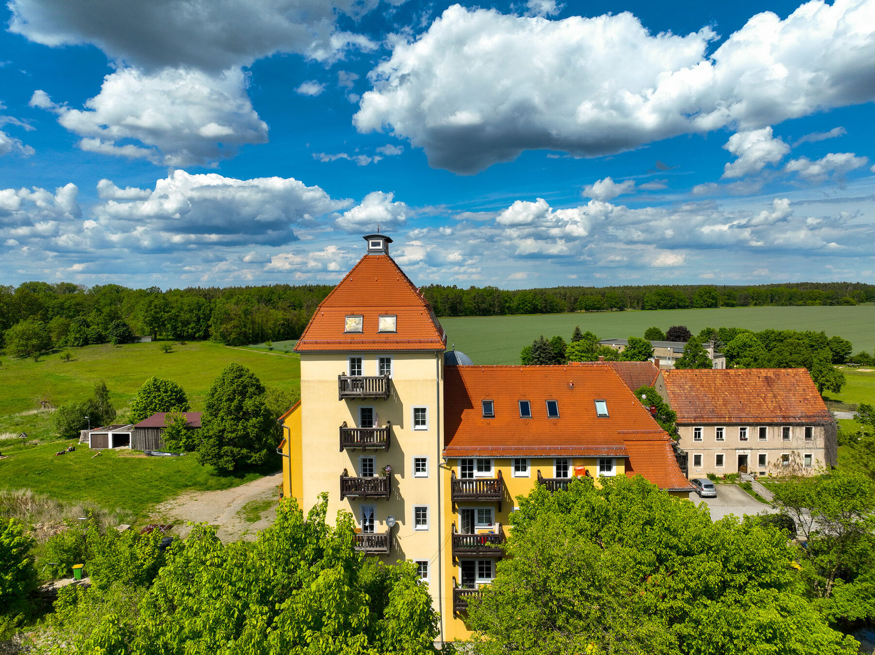 Schlossmühle mit Turm und Nebengebäuden vor weiter Landschaft